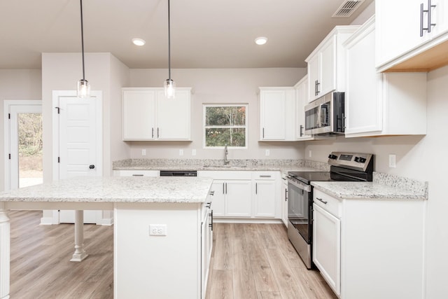 kitchen with a kitchen island, light wood-style floors, stainless steel appliances, and visible vents