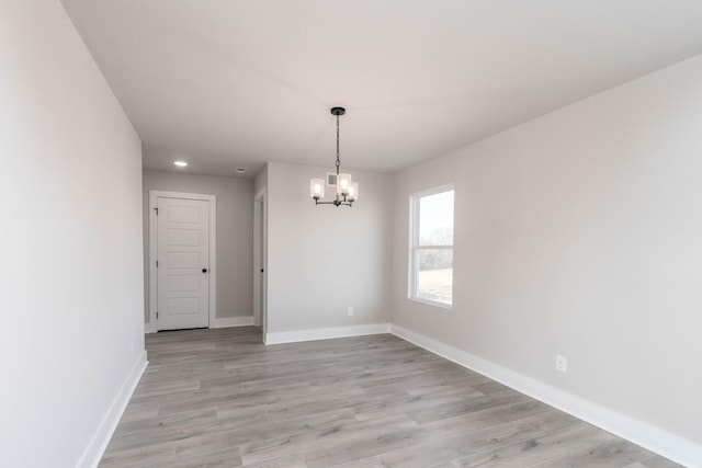 unfurnished dining area featuring baseboards, an inviting chandelier, and light wood-type flooring
