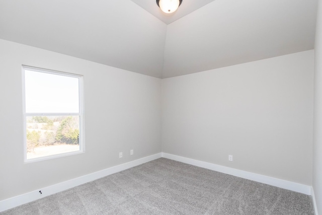 unfurnished room featuring lofted ceiling, carpet, and baseboards