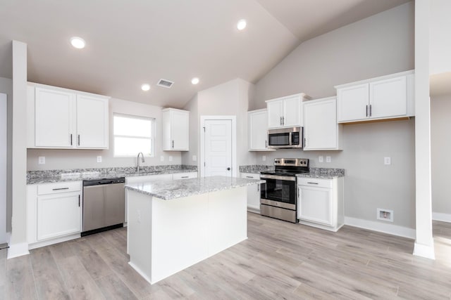 kitchen featuring lofted ceiling, visible vents, a sink, white cabinetry, and appliances with stainless steel finishes
