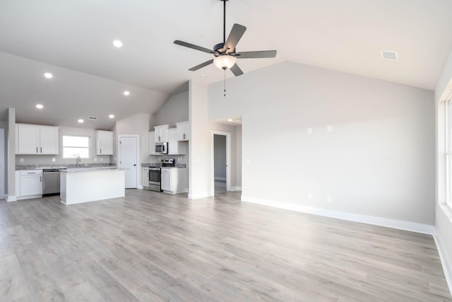 unfurnished living room featuring a ceiling fan, baseboards, a sink, high vaulted ceiling, and light wood-type flooring