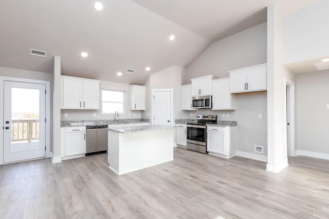 kitchen featuring a sink, visible vents, white cabinetry, a kitchen island, and appliances with stainless steel finishes