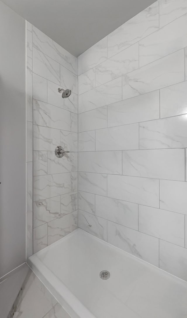 full bath with marble finish floor and a tile shower