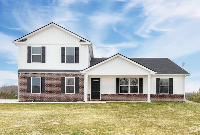 view of front of house featuring roof with shingles, brick siding, and a front yard