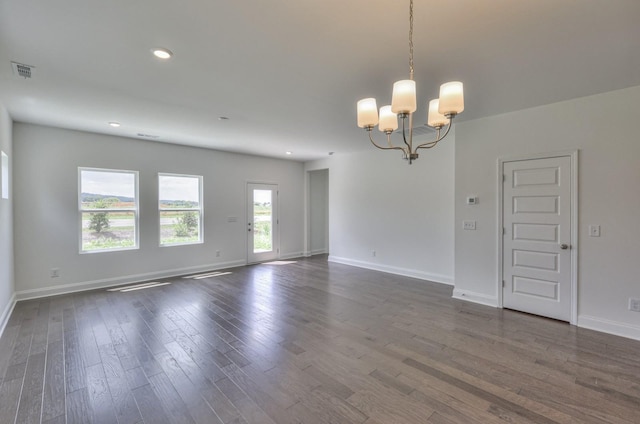 empty room featuring baseboards, dark wood-style flooring, an inviting chandelier, and visible vents