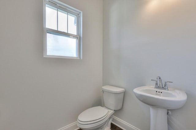 half bathroom featuring baseboards and toilet