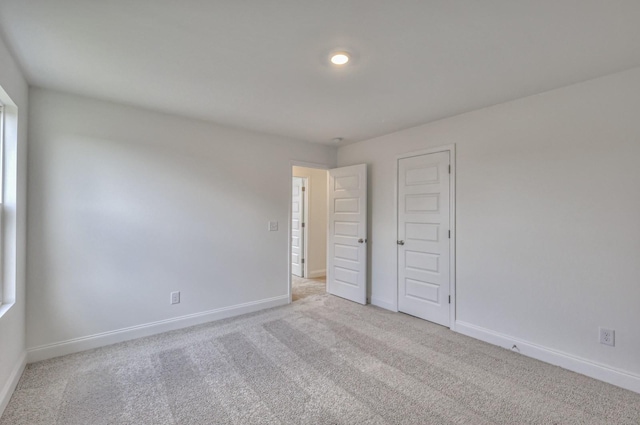 unfurnished bedroom featuring baseboards and light colored carpet