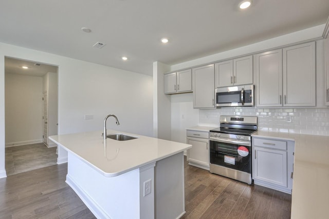 kitchen with a sink, tasteful backsplash, dark wood finished floors, gray cabinetry, and appliances with stainless steel finishes