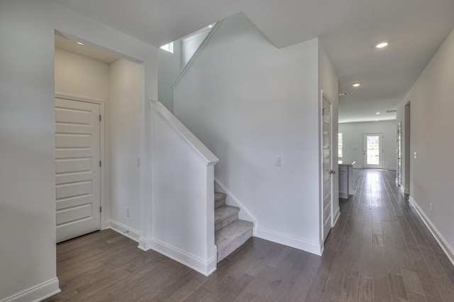 stairs with wood finished floors, baseboards, and recessed lighting