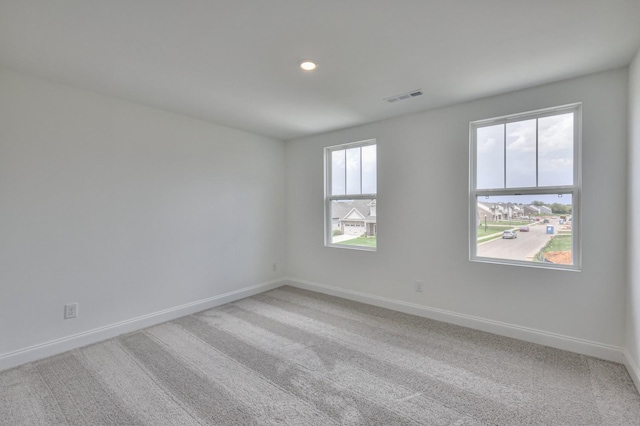 empty room with light colored carpet, visible vents, baseboards, and recessed lighting