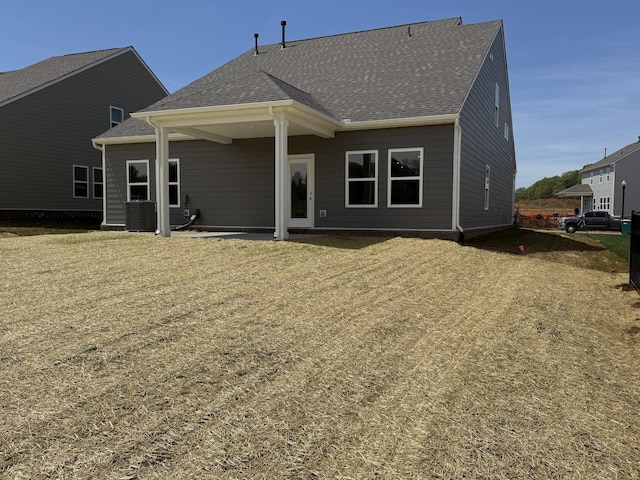 back of property with a shingled roof and central air condition unit