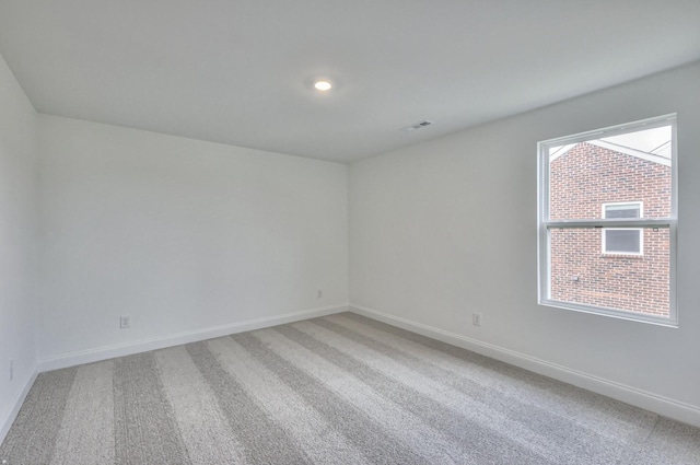 empty room with baseboards, visible vents, and light colored carpet