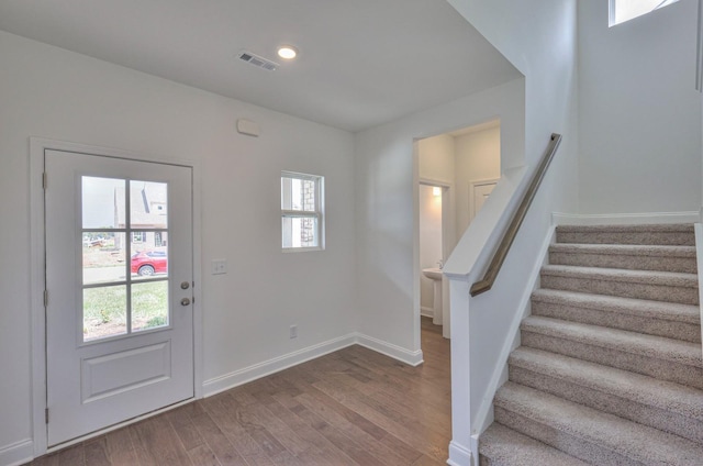 entrance foyer featuring stairs, a wealth of natural light, baseboards, and wood finished floors