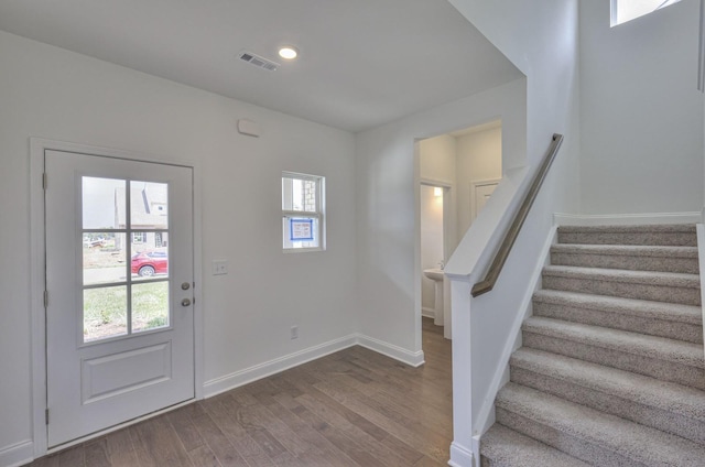 foyer featuring plenty of natural light, dark wood-style flooring, baseboards, and stairs