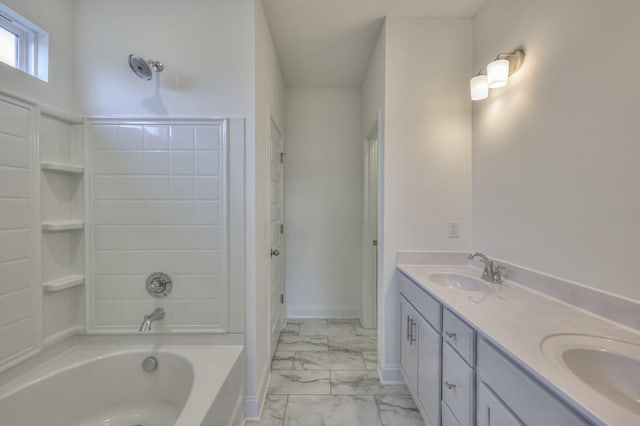 full bath featuring marble finish floor, a bathing tub, a sink, and double vanity