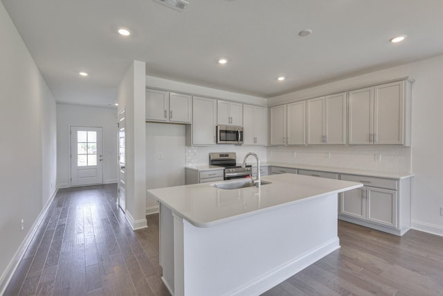 kitchen featuring a sink, dark wood-type flooring, baseboards, appliances with stainless steel finishes, and decorative backsplash