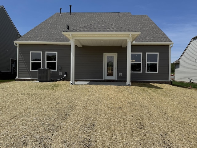 back of house featuring central AC unit and a shingled roof