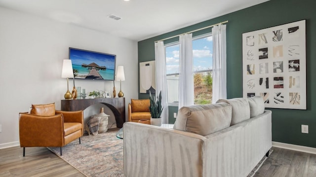 living room featuring baseboards, visible vents, and wood finished floors