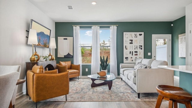living area with visible vents, wood finished floors, and a healthy amount of sunlight