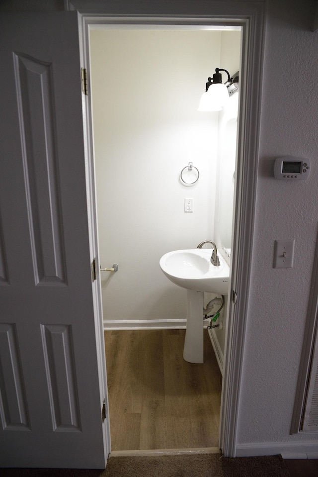 bathroom with baseboards, a sink, and wood finished floors