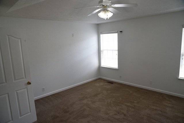 carpeted empty room with visible vents, baseboards, and ceiling fan