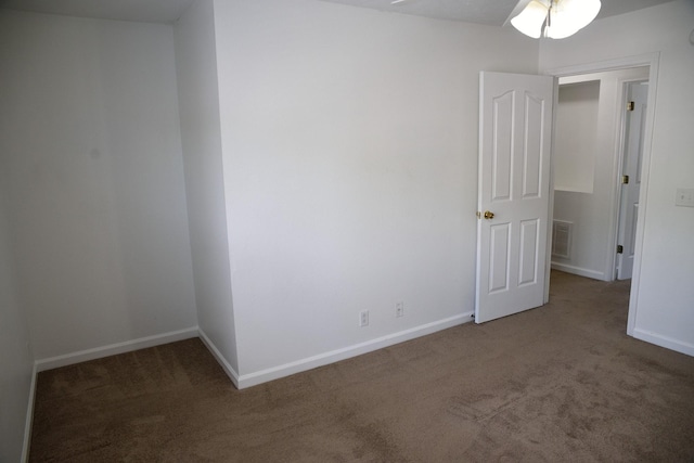 carpeted empty room with baseboards, a ceiling fan, and visible vents