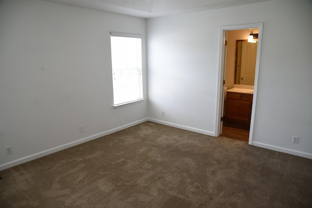 unfurnished bedroom with connected bathroom, baseboards, and carpet floors