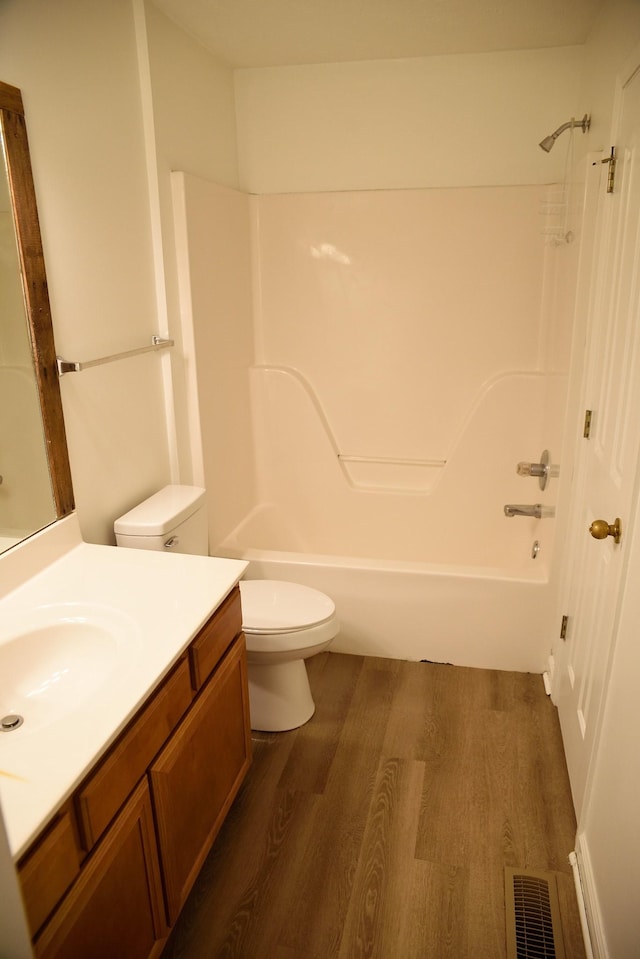 bathroom featuring toilet, tub / shower combination, wood finished floors, visible vents, and vanity