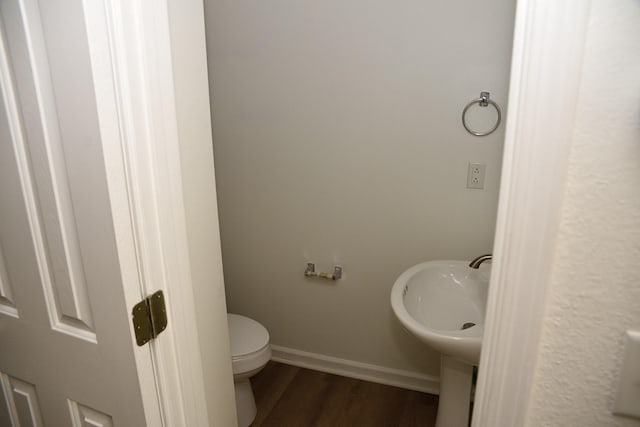 bathroom featuring toilet, wood finished floors, and baseboards