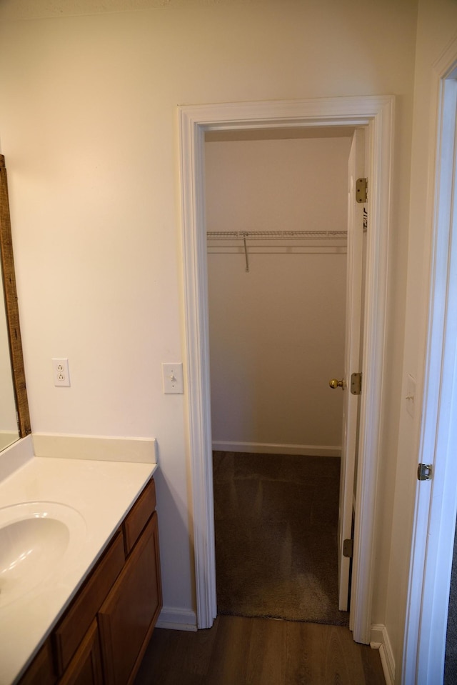 bathroom featuring vanity, a walk in closet, and baseboards