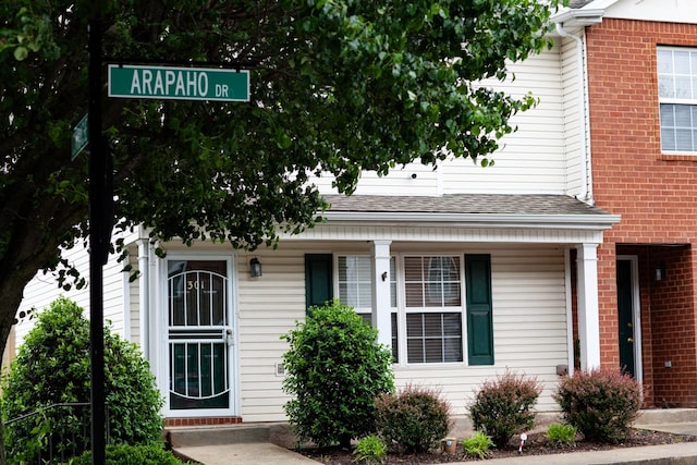 view of front of home with a shingled roof and brick siding