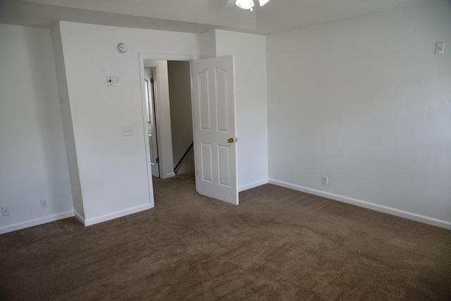 empty room with baseboards, a ceiling fan, and dark carpet