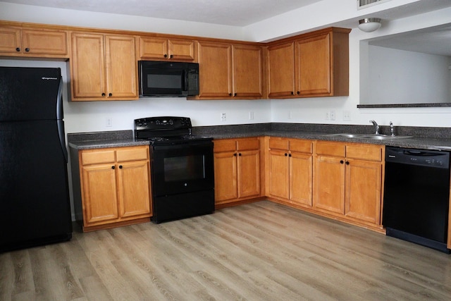 kitchen with light wood-style floors, brown cabinets, black appliances, and a sink