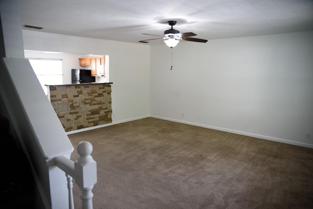spare room with carpet, visible vents, baseboards, and ceiling fan