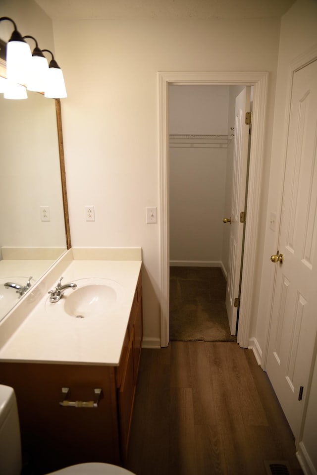 bathroom with toilet, visible vents, wood finished floors, and vanity