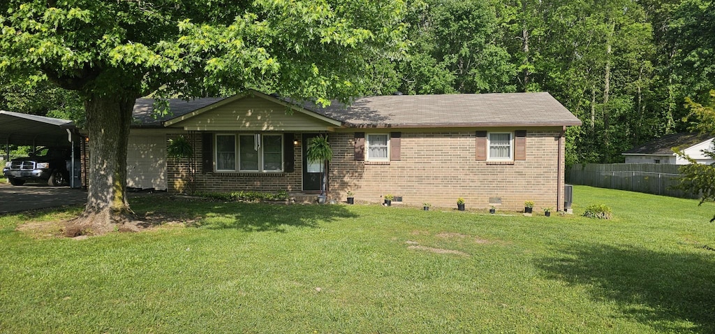 single story home featuring a front lawn, brick siding, a detached carport, and fence