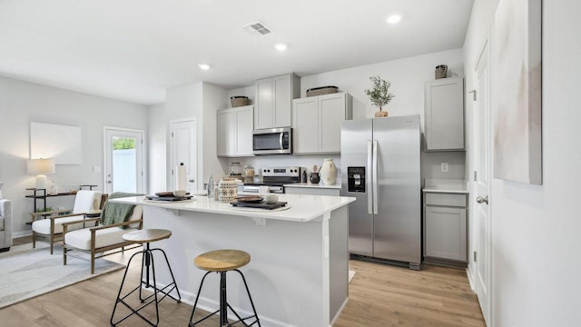 kitchen featuring a breakfast bar area, light wood-type flooring, visible vents, and appliances with stainless steel finishes