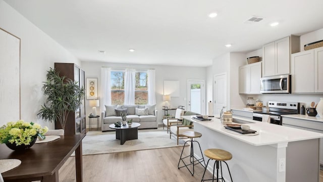 kitchen featuring a breakfast bar, stainless steel appliances, light countertops, light wood-style floors, and a kitchen island