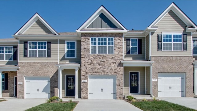 multi unit property featuring board and batten siding, a garage, stone siding, and driveway