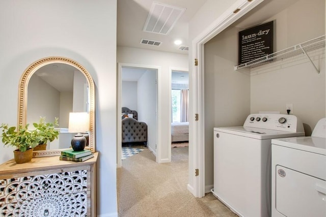 washroom with washing machine and dryer, visible vents, and light colored carpet