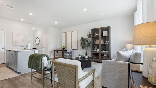 living room featuring light wood-type flooring, visible vents, and recessed lighting