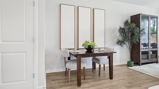 dining area with light wood finished floors and baseboards