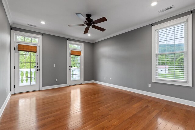spare room featuring crown molding, wood-type flooring, a ceiling fan, and visible vents