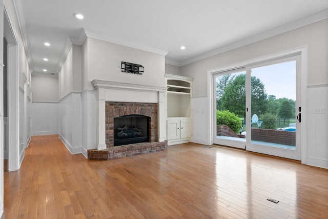 unfurnished living room with recessed lighting, light wood-style floors, a fireplace, and crown molding