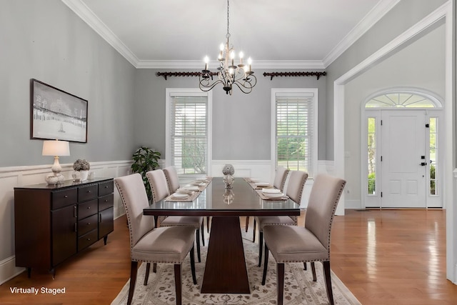 dining area featuring wainscoting, an inviting chandelier, crown molding, and wood finished floors
