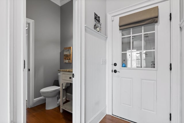 interior space featuring toilet, crown molding, and wood finished floors