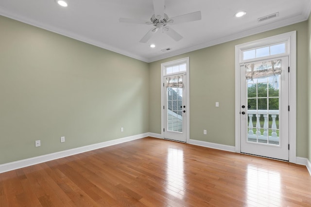 interior space featuring a ceiling fan, light wood finished floors, visible vents, and crown molding