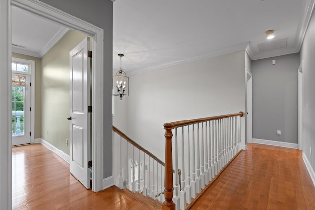 hall featuring an upstairs landing, crown molding, and wood finished floors