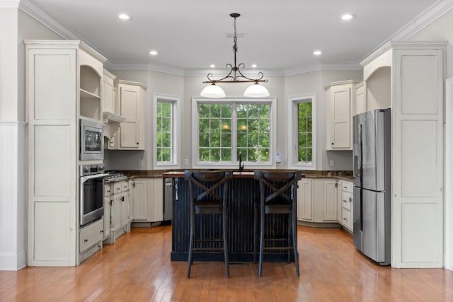 kitchen featuring light wood-type flooring, visible vents, a center island, dark countertops, and appliances with stainless steel finishes