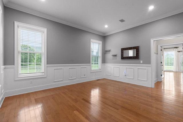 unfurnished living room with light wood finished floors, visible vents, wainscoting, ornamental molding, and recessed lighting
